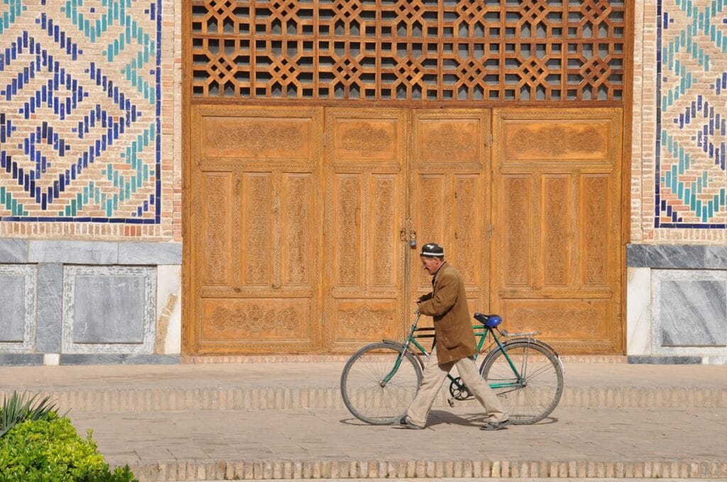 Voyage en Ouzbékistan en 2025 - Homme en vélo devant un monument de Samarcande - Visiter Samarcande - Agence de voyage NostalAsie ANN