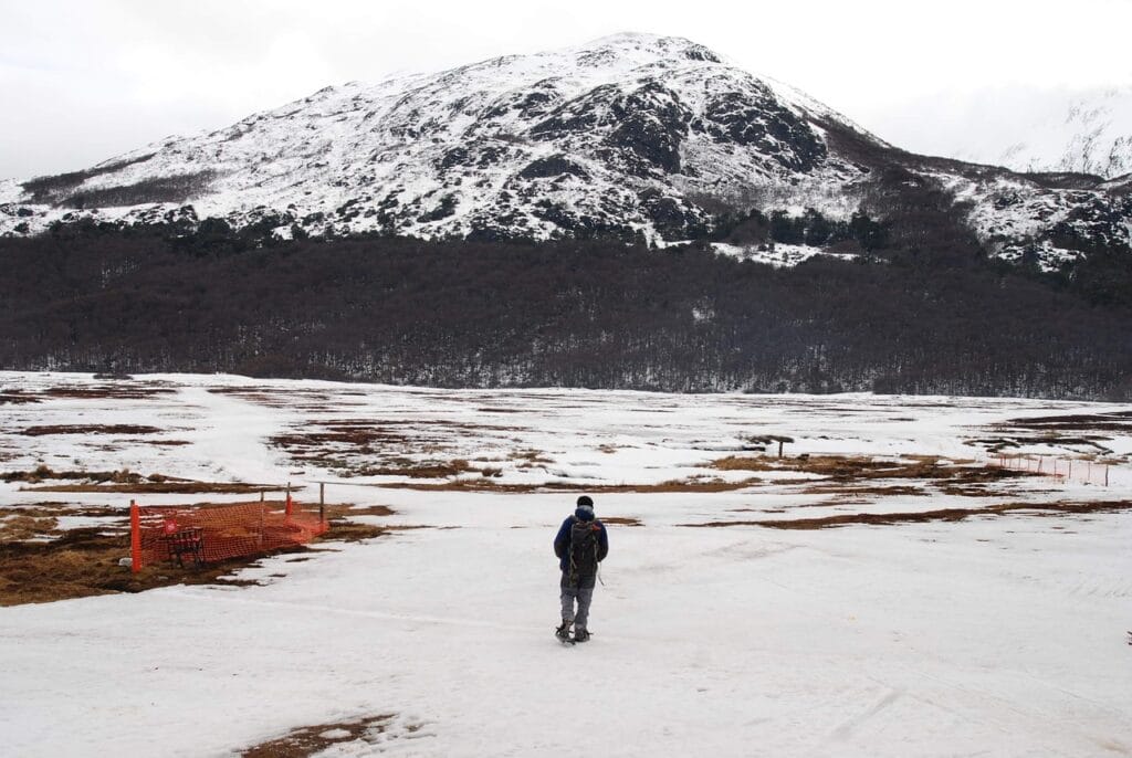Voyage en Argentine en 2025 - Ushuaia, la ville du bout du monde - Visiter Ushuaia - Montagnes enneigées dans le parc national Tierra del Fuego avec homme qui marche - Agence de voyage NostaLatina ANN