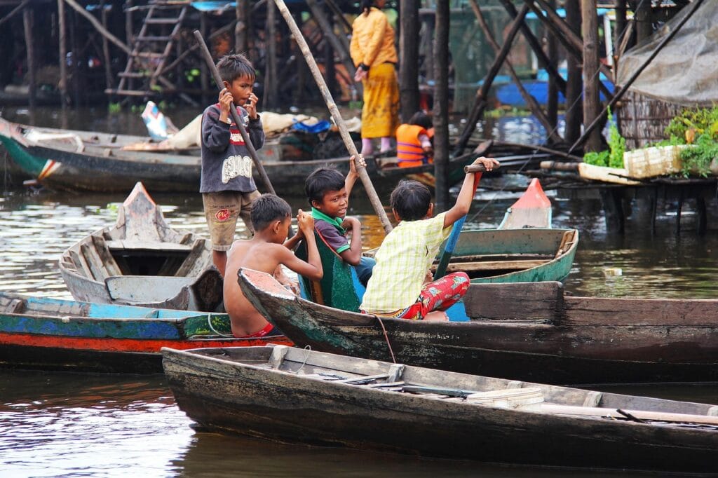 Voyage au Cambodge en 2026 - Enfants jouant sur les bateaux du lac Tonlé Sap - Voyage sur mesure avec NostalAsia ANN
